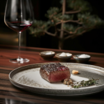 Wagyu beef centerpiece on dark wood table with gourmet accompaniments and red wine, symbolizing luxury dining.